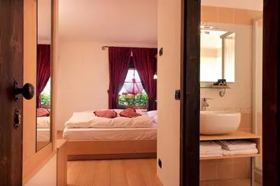 a bedroom with a bed and a sink and a mirror at Hotel Fonte Dei Veli in Panchia
