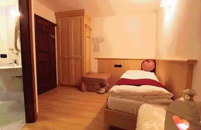a bedroom with a bed and a bathroom with a sink at Hotel Fonte Dei Veli in Panchia