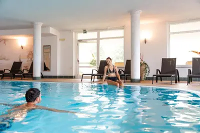 a man and a woman sitting in a swimming pool at Hotel Asterbel in Braies