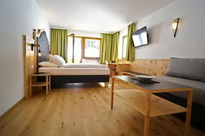 a deck with a chair and a view of the mountains at Hotel Asterbel in Braies