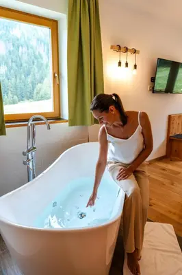 a woman is sitting in a bath tub at Hotel Asterbel in Braies