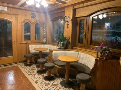 a room with two tables and stools and windows at Hotel Stella in Moena
