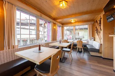 a restaurant with a bench and tables and windows at Hotel Stella in Moena