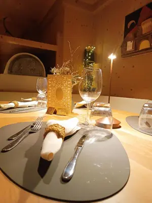a table with a plate with fork and knife and wine glasses at Hotel Stella in Moena