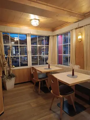 two tables and chairs in a room with windows at Hotel Stella in Moena