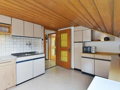 a kitchen with white cabinets and a wooden ceiling at Apartment Demetz by Interhome in Ortisei