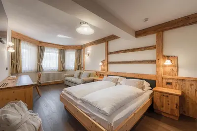 a bedroom with a large bed and a desk at Renè Dolomites Boutique Hotel in Pozza di Fassa