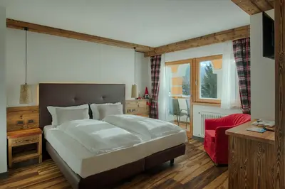 a bedroom with a large bed and a red chair at Renè Dolomites Boutique Hotel in Pozza di Fassa