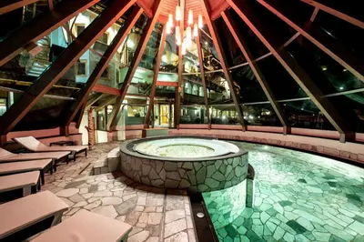 a large building with a pool in the middle at Renè Dolomites Boutique Hotel in Pozza di Fassa