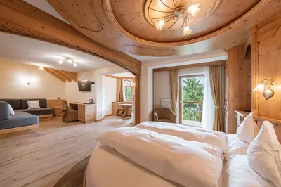 a bedroom with a large bed with a ceiling at Renè Dolomites Boutique Hotel in Pozza di Fassa