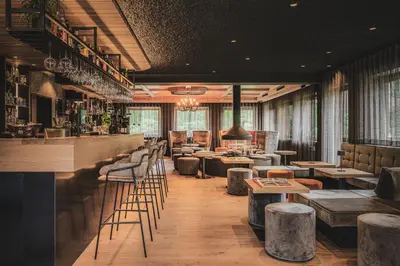 a restaurant with a bar with stools and tables at Hotel Christof in Monguelfo