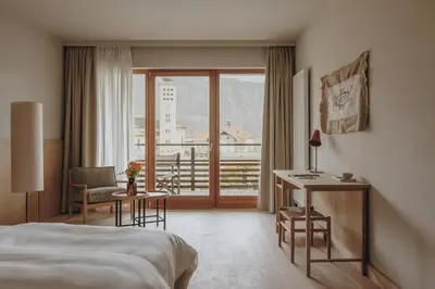 a hotel room with a bed and a desk and a window at Hotel Schwarzschmied, a Member of Design Hotels in Lana