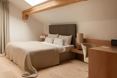 a bedroom with a bed and a desk with a chair at Hotel Schwarzschmied, a Member of Design Hotels in Lana