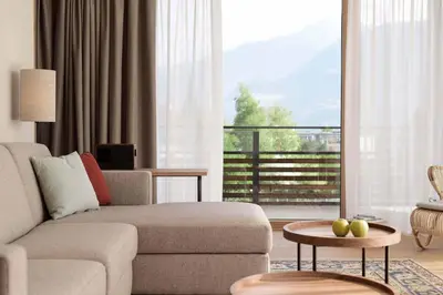 a living room with a couch and a large window at Hotel Schwarzschmied, a Member of Design Hotels in Lana