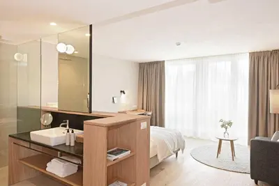 a bathroom with a sink and a bed and a mirror at Hotel Schwarzschmied, a Member of Design Hotels in Lana