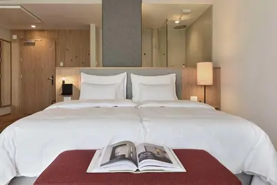 a bedroom with a large white bed with a book on a table at Hotel Schwarzschmied, a Member of Design Hotels in Lana