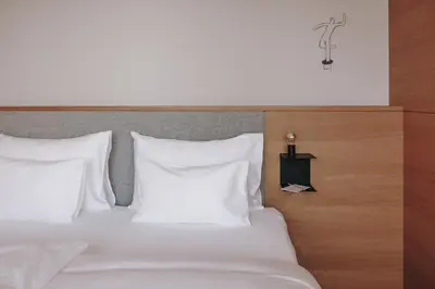 a bed with white pillows and a wooden head board at Hotel Schwarzschmied, a Member of Design Hotels in Lana
