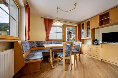a kitchen with a table and chairs and a television at Residence Oberhauser in Valdaora
