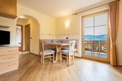 a dining room with a table and a large window at Residence Oberhauser in Valdaora