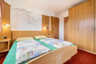 a bedroom with a large bed with wooden cabinets at Residence Oberhauser in Valdaora