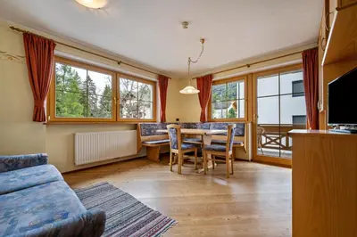 a living room with a table and chairs and windows at Residence Oberhauser in Valdaora