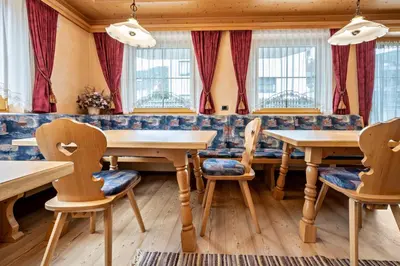 a restaurant with wooden tables and chairs and windows at Residence Oberhauser in Valdaora