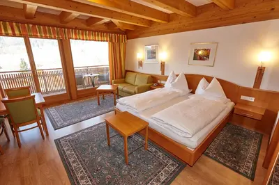 a bedroom with a bed and a living room at Hotel Brötz in Rasùn di Sotto