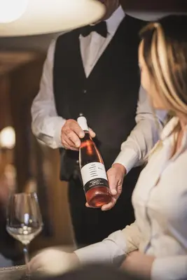 a man holding a bottle of wine next to a woman at Hotel Brötz in Rasùn di Sotto