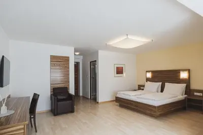 a bedroom with a bed and a table and a desk at Hotel Brötz in Rasùn di Sotto