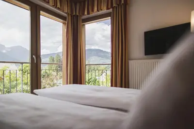 a bedroom with two beds and a large window at Hotel Brötz in Rasùn di Sotto