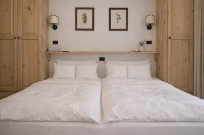 a bed with white sheets and pillows on it at Sporting Clubresidence in San Martino di Castrozza