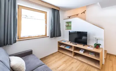 a living room with a couch and a flat screen tv at Putzerhof in Siusi