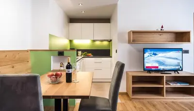 a kitchen with a dining table and a television at Putzerhof in Siusi