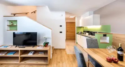a kitchen and dining room with a dining table and a television at Putzerhof in Siusi