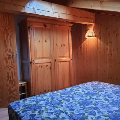 a bedroom with wooden walls and a bed with a blue blanket at Casa Penia 2 in Canazei