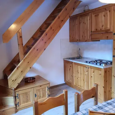 an attic kitchen with wooden cabinets and a staircase at Casa Penia 2 in Canazei