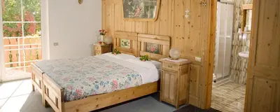 a bedroom with a bed and a bathroom with a sink at Hotel Rosa Resort in Cavareno