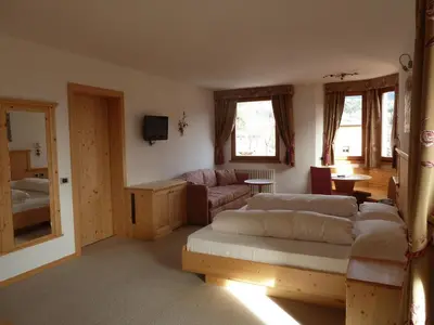 a living room with a bed and a couch at Hotel Rosa Resort in Cavareno