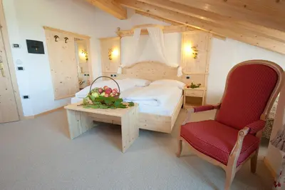 a bedroom with a bed and a table and a chair at Hotel Rosa Resort in Cavareno