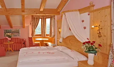 a bedroom with a bed and a couch in a room at Hotel Rosa Resort in Cavareno