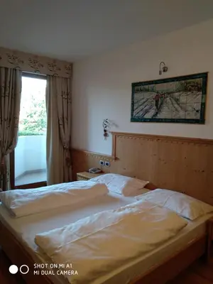 a bedroom with a bed and a window with a map on the wall at Hotel Rosa Resort in Cavareno
