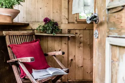 a red pillow sitting in a wooden rocking chair at Hotel Braunsbergerhof in Lana