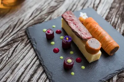 a plate of food with meat and vegetables on a table at Hotel Braunsbergerhof in Lana