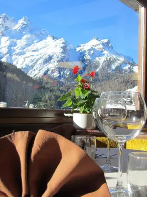 a table with wine glasses and a view of mountains at Hotel Corona in Val di Zoldo