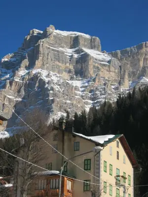 a building in front of a mountain with snow on it at Hotel Corona in Val di Zoldo