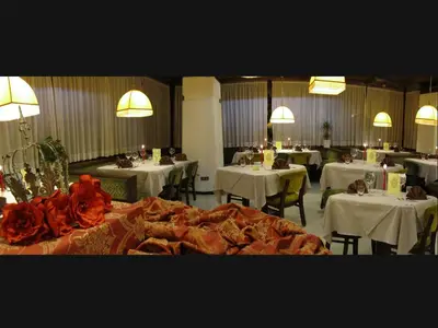 a dining room with tables and white clothed tables with tablesktop at Hotel Corona in Val di Zoldo