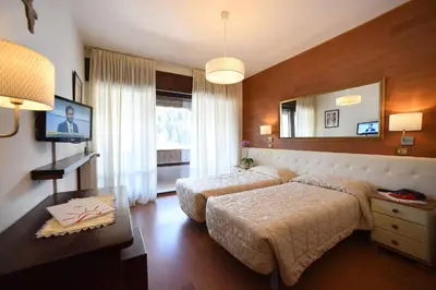 a hotel room with two beds and a mirror at Hotel Corona in Val di Zoldo