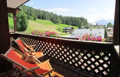 two chairs on a balcony with a view of a valley at Hotel Corona in Val di Zoldo