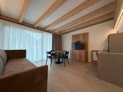a bedroom with a bed and a tv on the wall at Liz Hotel & Apartments in Predazzo