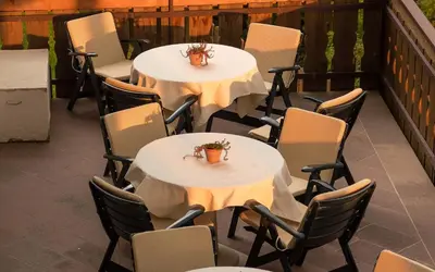 two tables and chairs with flowers on a patio at Hotel ADLER Carezza in Nova Levante